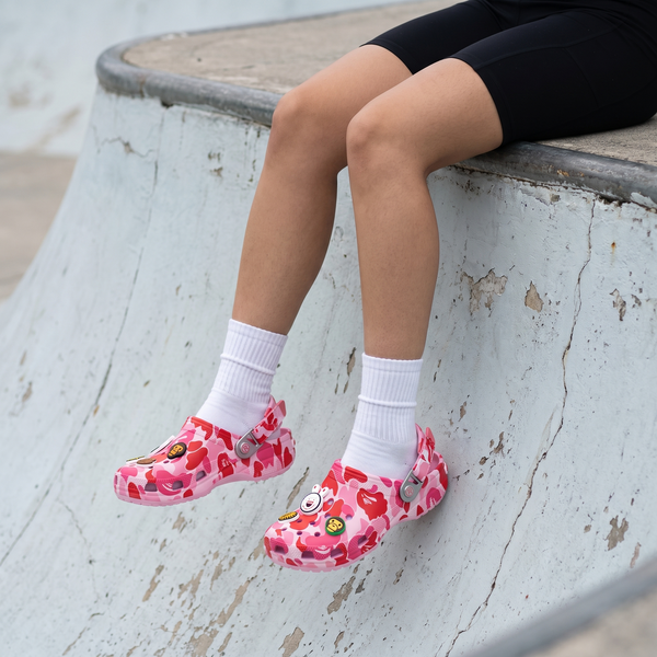 Pink camo SYDZ foam clogs worn on a skatepark ledge